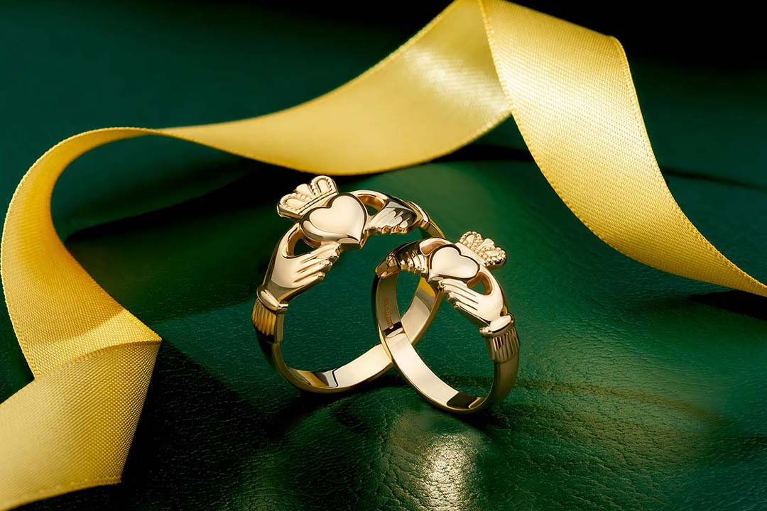 a set of gold Claddagh rings on the green background