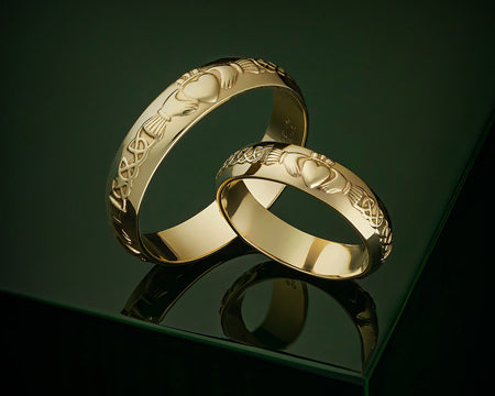a styled image of two gold claddagh wedding bands