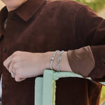 a lifestyle image of a model wearing a bracelet stack of Claddagh tennis bracelet and celtic knot link bracelet