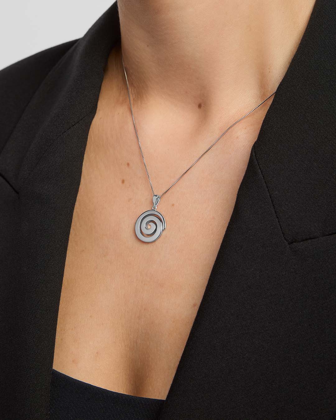 Silver Celtic spiral pendant necklace from Solvar on a person wearing a black blazer.