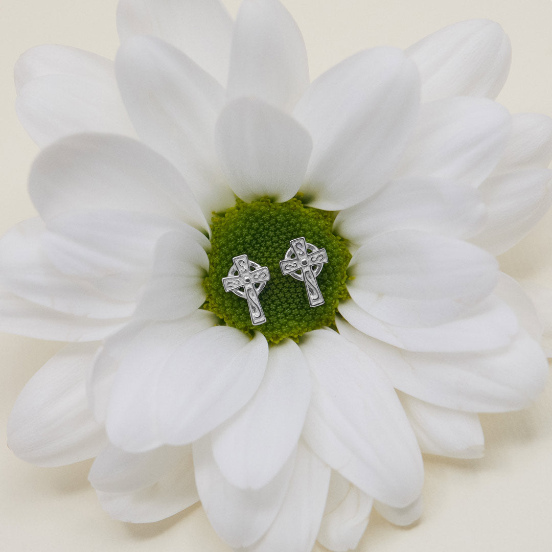 lifestyle image of kids celtic cross stud earrings presented on a spring flower 