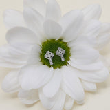 lifestyle image of kids celtic cross stud earrings presented on a spring flower 