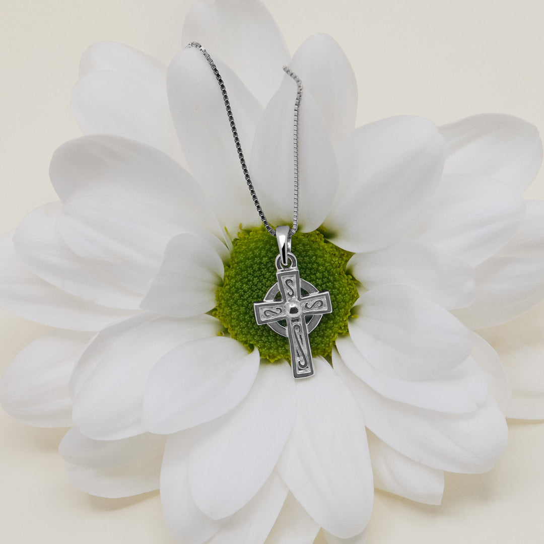 lifestyle image of kid's silver celtic cross pendant presented on a spring flower