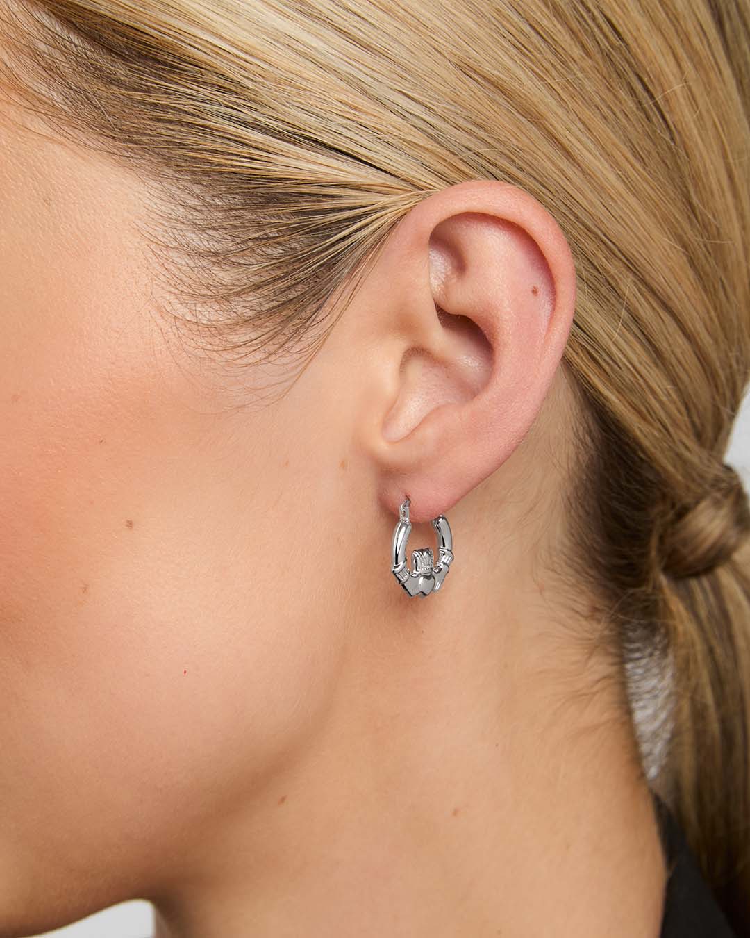 close-up image of claddagh  hoop earrings on a female model