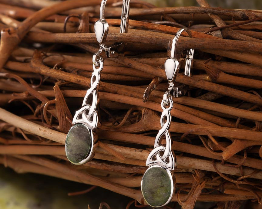 lifestyle image of  celtic drop earrings on green marble background