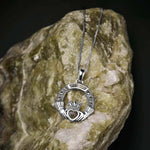 lifestyle image of silver Connemara marble  Claddagh necklace displayed on green marble 