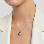 Person wearing a silver necklace with a shamrock pendant on a white background