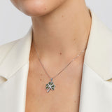 Person wearing a silver necklace with a shamrock pendant on a white background