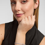 Woman wearing a silver Claddagh cz tennis bracelet on a plain background