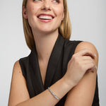 Woman wearing a black sleeveless top and silver Trinity Knot bracelet on a plain background
