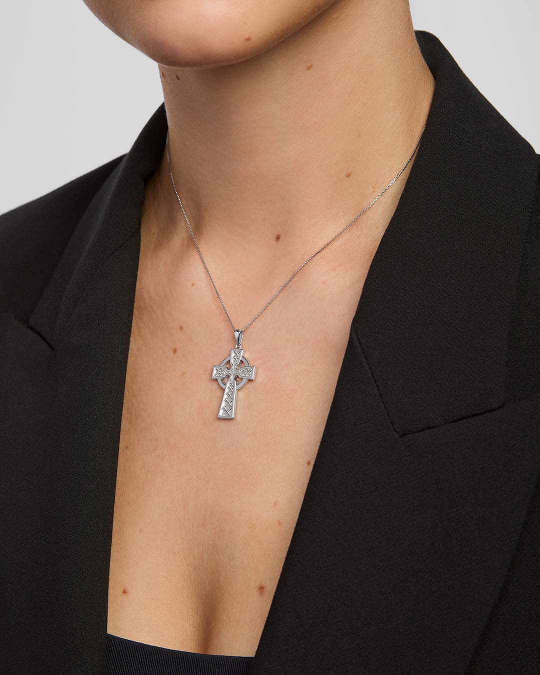 close-up image of double-sided embossed celtic cross pendant on a model