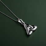 lifestyle image of double-sided trinity knot pendant on green background
