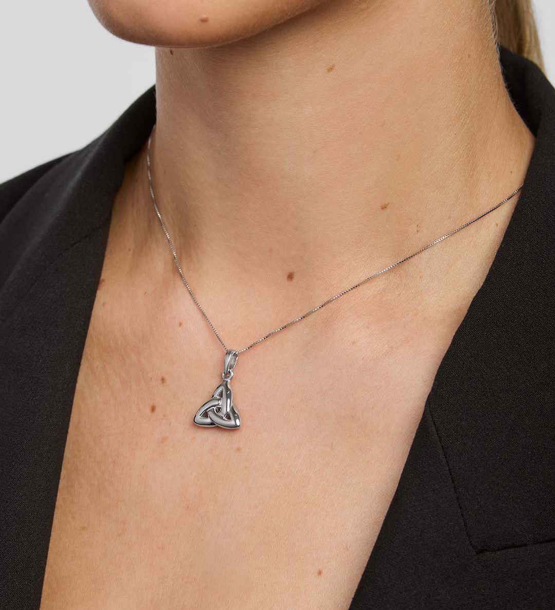 Silver necklace with a double-sided trinity knot pendant on a person wearing a black blazer.