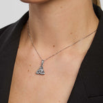 Silver necklace with a double-sided trinity knot pendant on a person wearing a black blazer.