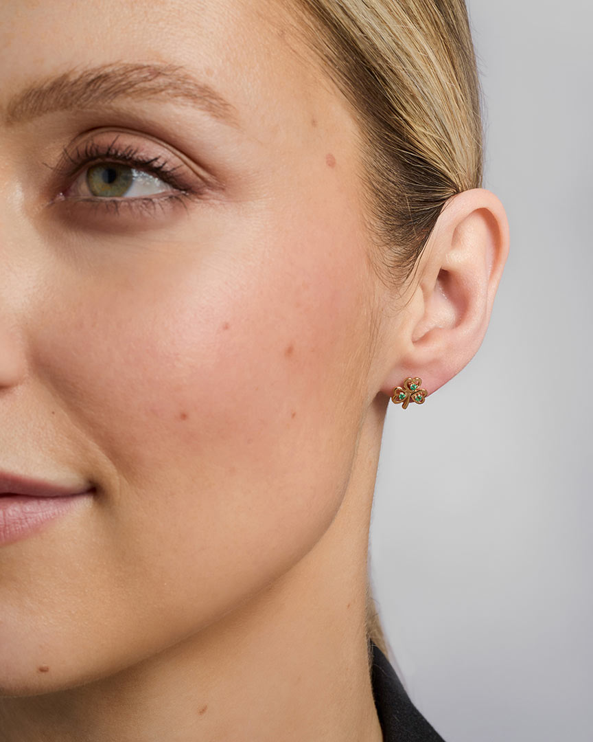 close-up image of yellow gold emerald shamrock earrings on a female model