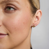close-up image of yellow gold emerald shamrock earrings on a female model