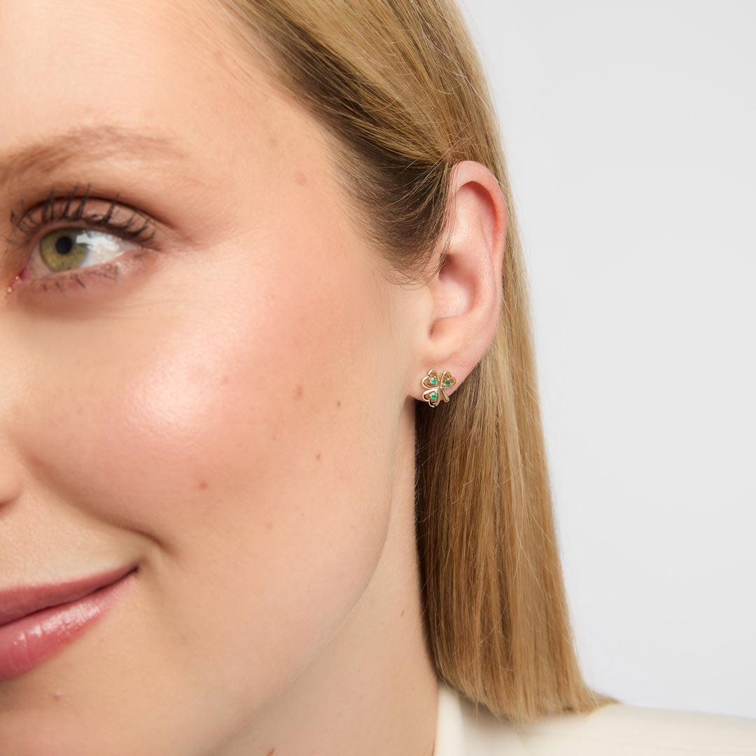 Close-up of a woman wearing a pair of emerald Shamrock earrings crafted in solid yellow gold