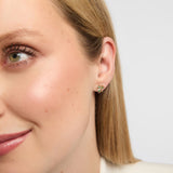 Close-up of a woman wearing a pair of emerald Shamrock earrings crafted in solid yellow gold