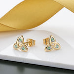 lifestyle image of emerald set gold trinity knot earrings