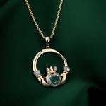 lifestyle image of emerald gold Claddagh pendant on green background