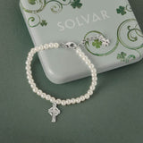 Celtic pearl bracelet with a silver Celtic cross charm on a green background