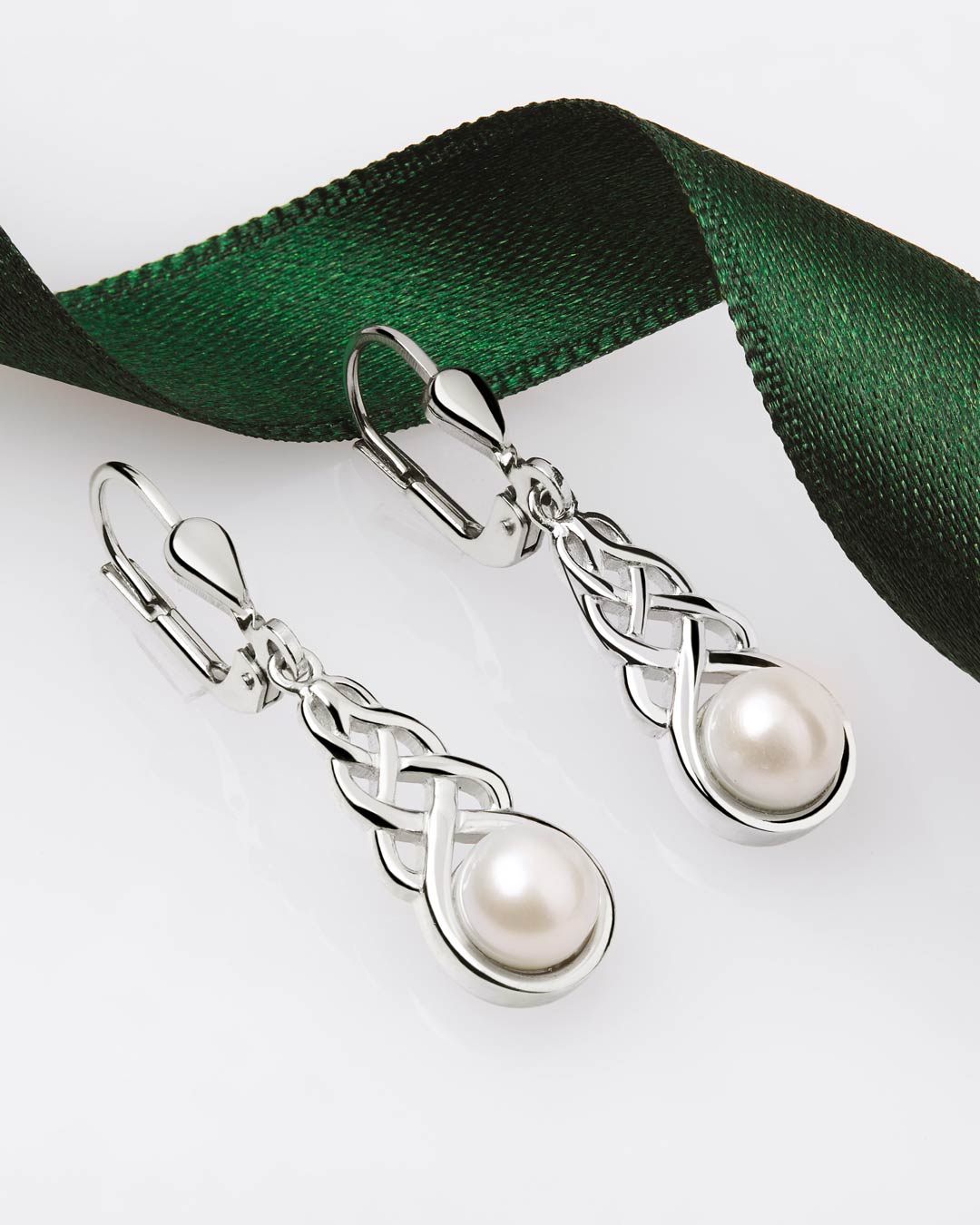 Silver Celtic Knot drop earrings with pearls on a white background with green ribbon
