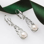 Silver Celtic Knot drop earrings with pearls on a white background with green ribbon