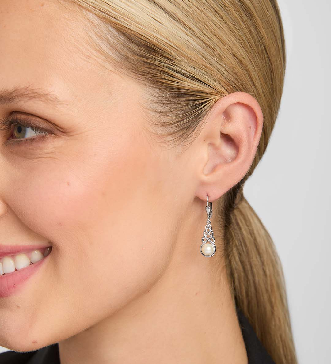 close-up image of freshwater pearl celtic drop earrings on a model
