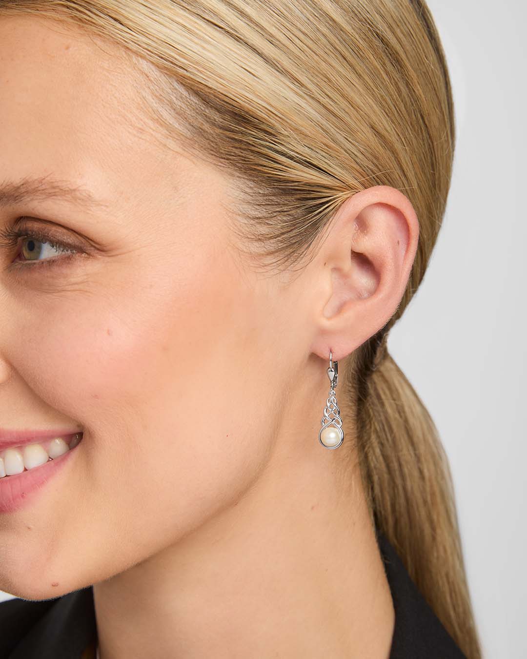 close-up image of freshwater pearl celtic drop earrings on a model