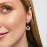 A close-up view of a woman adorned with traditional Claddagh drop earrings crafted in solid yellow gold