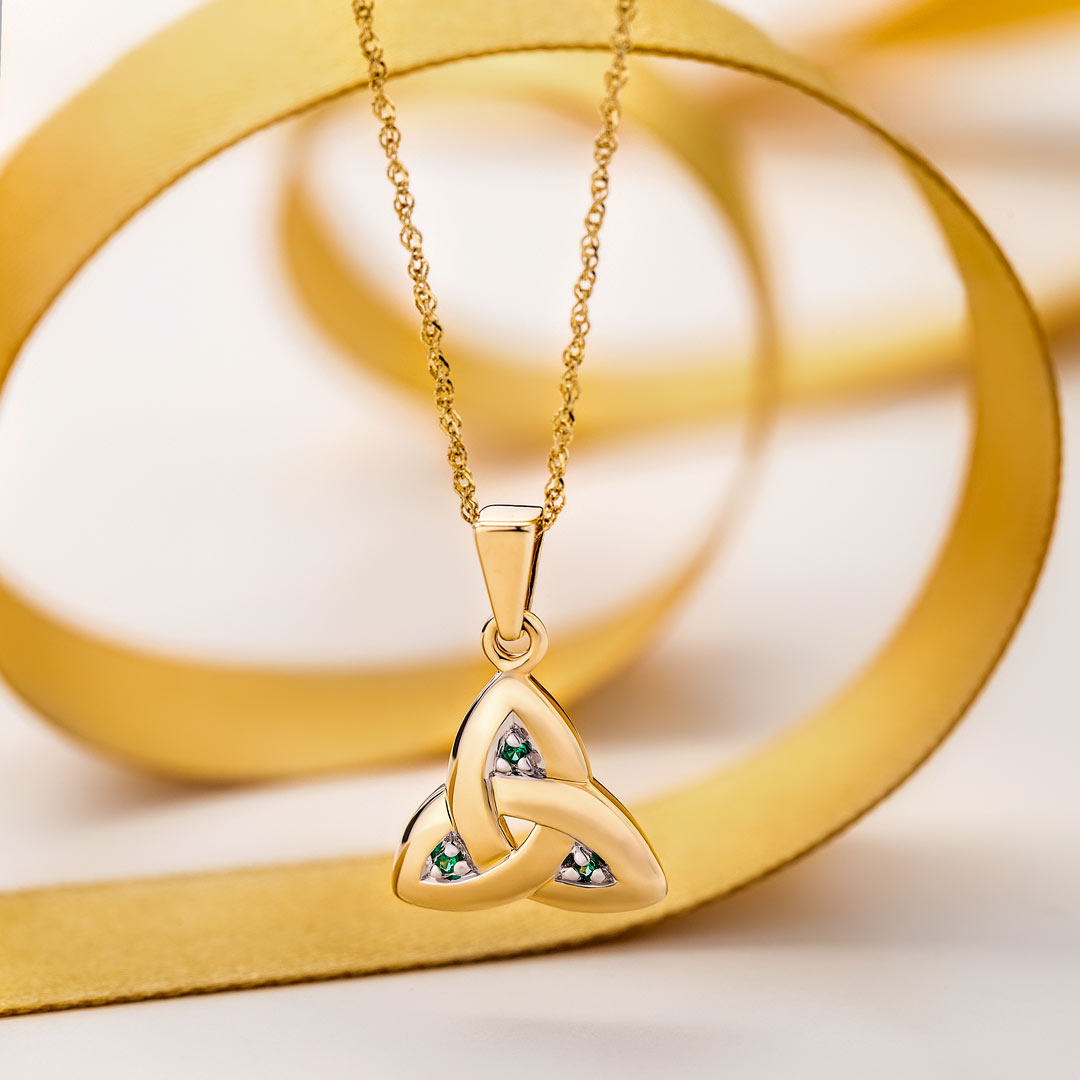 lifestyle image of gold emerald Trinity knot pendant from Solvar