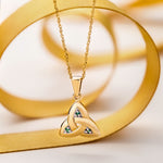 lifestyle image of gold emerald Trinity knot pendant from Solvar
