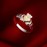 lifestyle image of gold hear Claddagh ring on red background