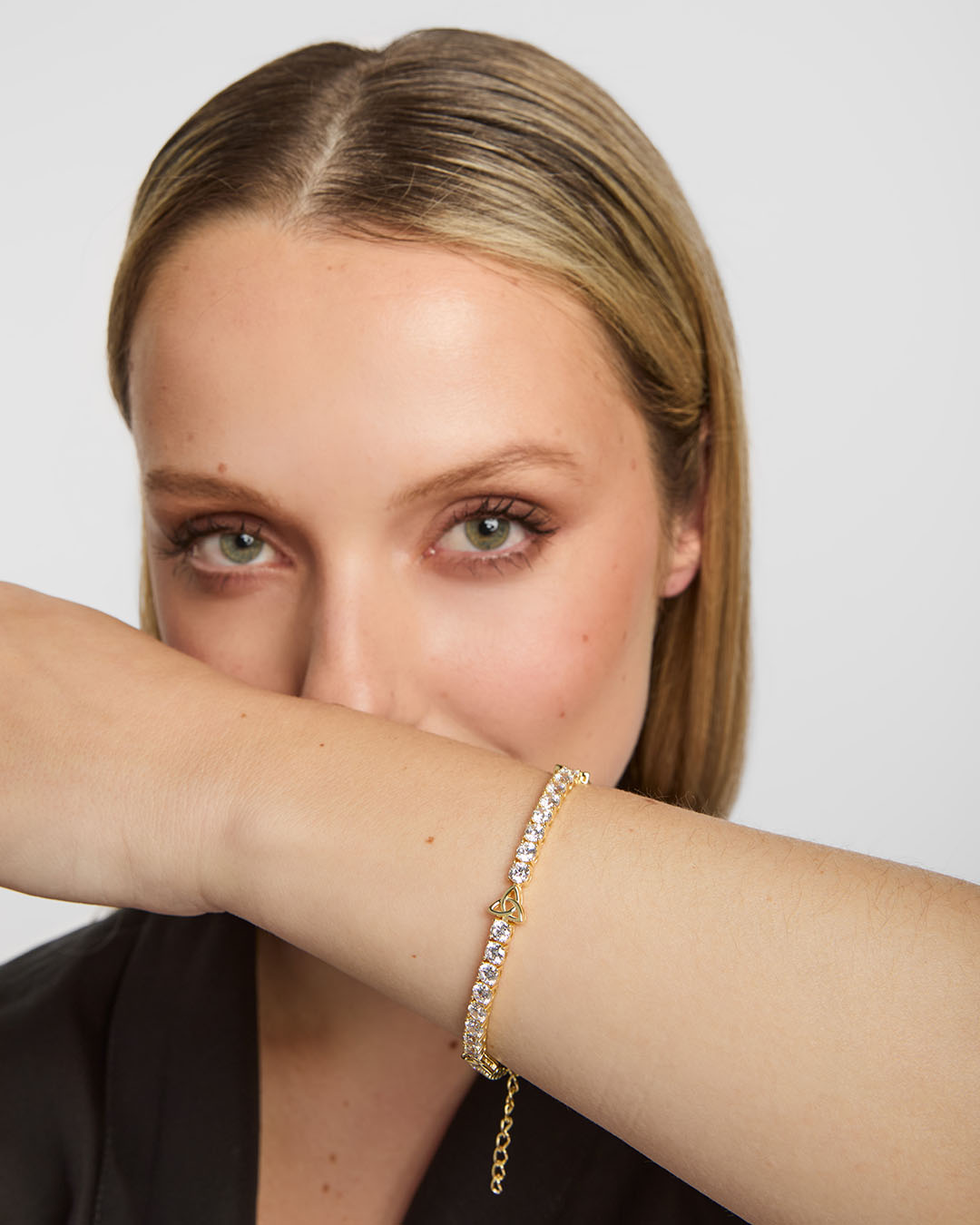 close-up image of gold plated trinity knot  celtic tennis bracelet on a woman's wrist