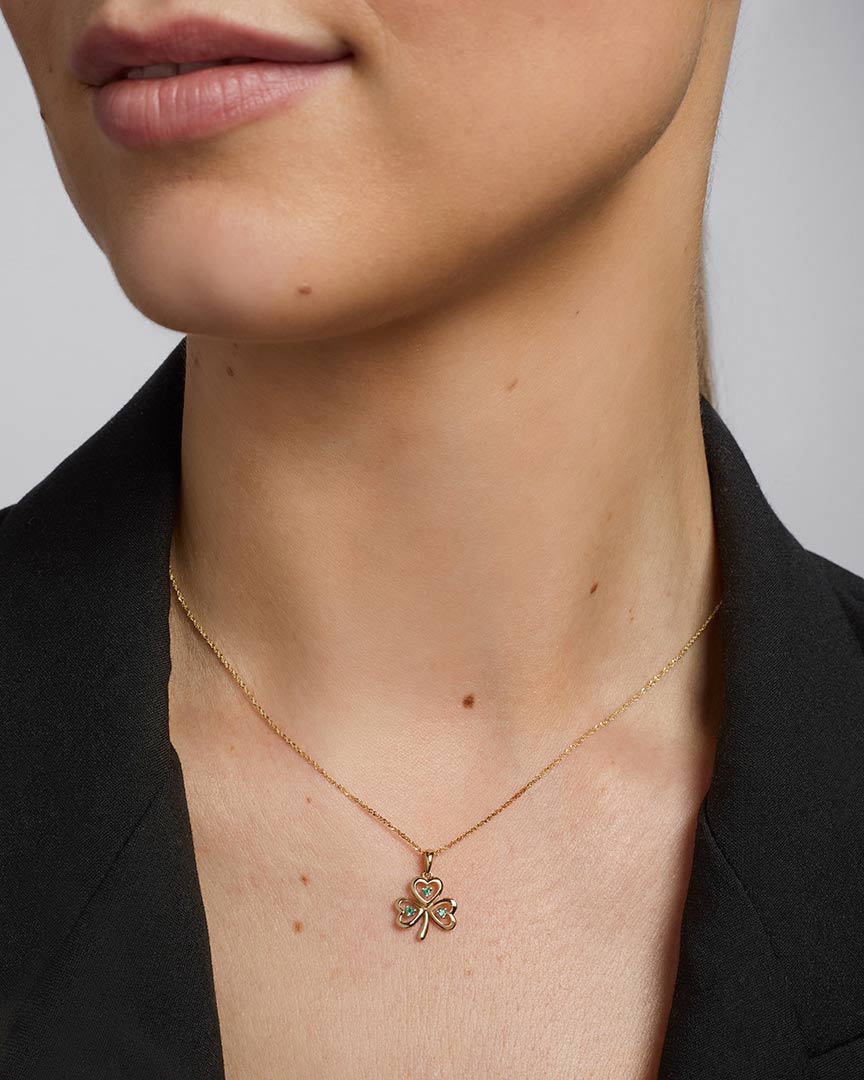 close-up image of gold emerald shamrock pendant on a female model