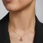close-up image of gold emerald shamrock pendant on a female model