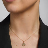 close-up image of gold emerald shamrock pendant on a female model
