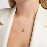close-up image of Solvar emerald set yellow gold shamrock necklace on a female model against neutral background