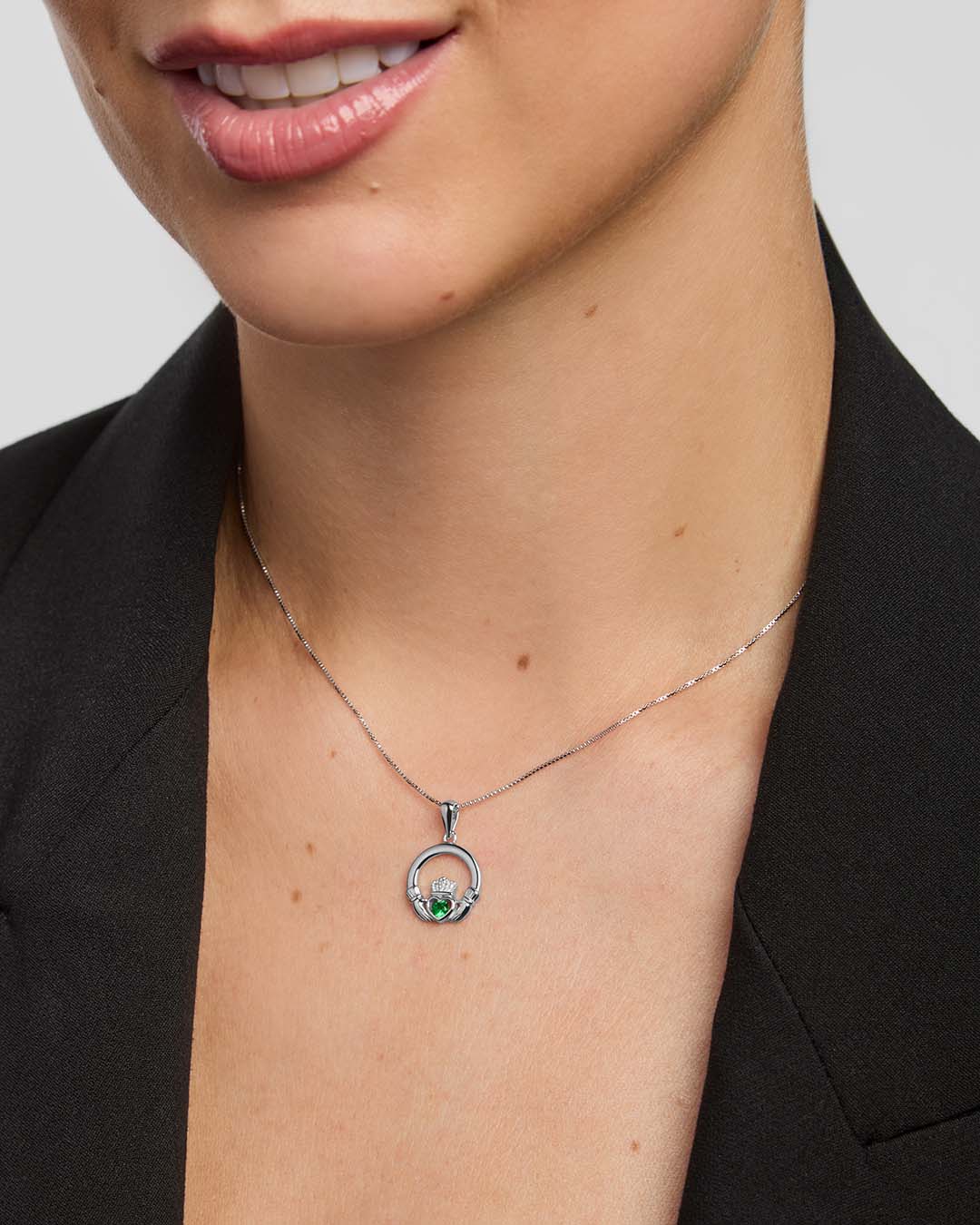 Claddagh necklace with a green stone  centre on a female model