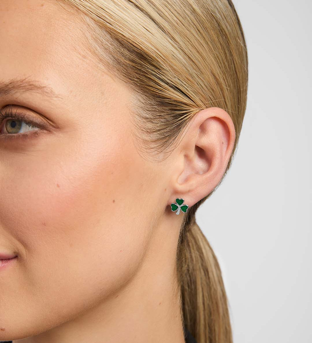 Close-up of a female model wearing green Shamrock stud earrings from Solvar