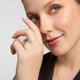 Green Cz Celtic Claddagh Band Ring, featuring a vivid green gemstone and sparkling accents, worn on a hand positioned beside the face against a light grey background.