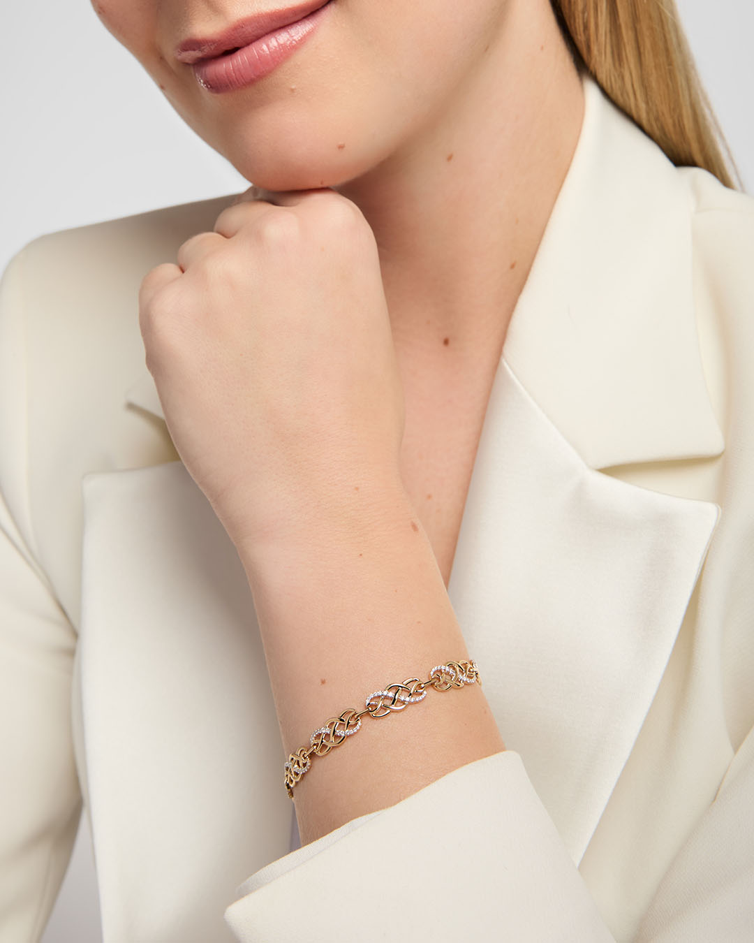 close-up image of yellow gold Celtic knot bracelet featuring a repeating pattern of openwork interlaced knots. Sections of the knotwork are accented with diamond set
