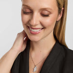 a close-up portrait of a female wearing a dark top and a thin chain necklace. The necklace features a large shiny Map of Ireland pendant