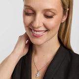 a close-up portrait of a female wearing a dark top and a thin chain necklace. The necklace features a large shiny Map of Ireland pendant