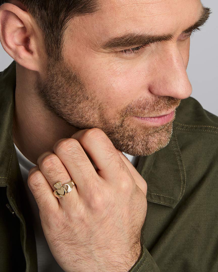 a male model wearing yellow gold heavy claddagh ring 