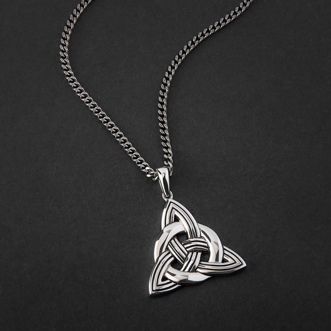 lifestyle image of large men's celtic knot pendant on a heavy silver flat curb chain 
