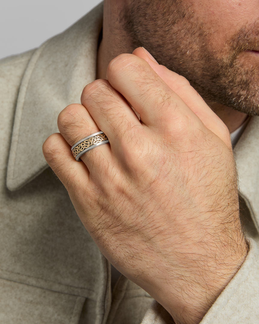 closeup image of mens gold and silver Celtic Trinity Knot band ring on a model