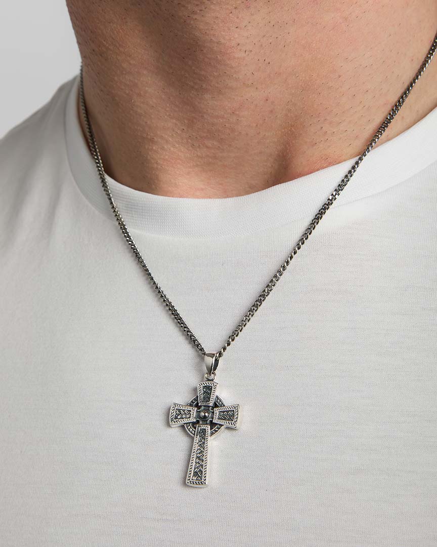 closeup image of men's oxidised silver Celtic Cross necklace on a model 