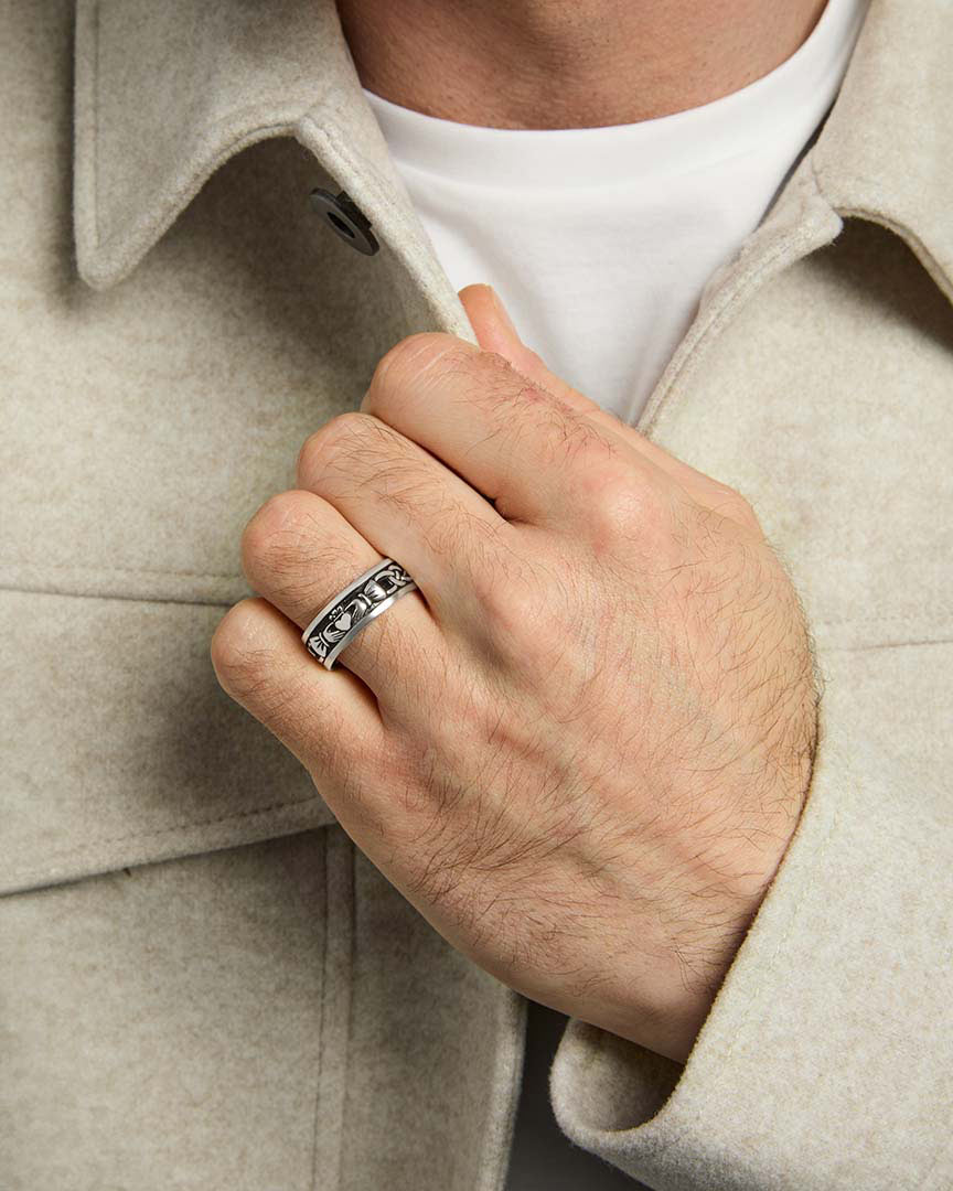 closeup image of mens silver claddagh band ring on a model