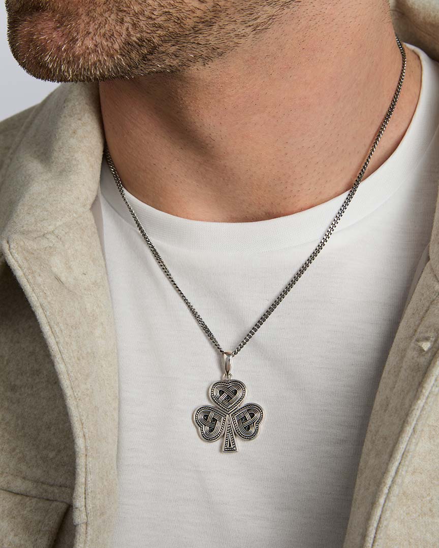 closeup image of oxidised silver men's heavy Celtic shamrock pendant on a model